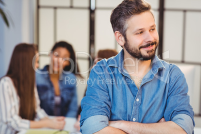 Businessman looking away against female coworkers