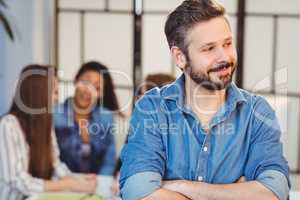 Businessman looking away against female coworkers