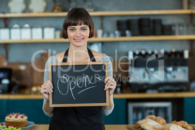 Smiling waitress showing slate with open sign