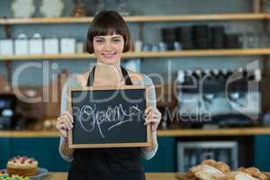 Smiling waitress showing slate with open sign