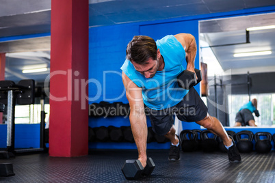 Young athlete lifting dumbbells in gym