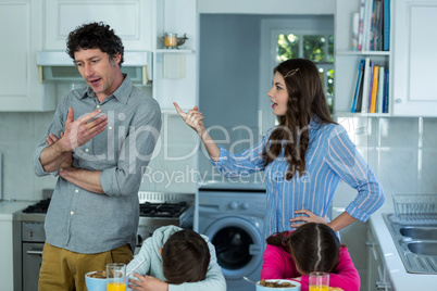 Upset children sitting while couple arguing with each other