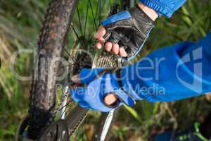 Close-up of male mountain biker fixing his bike chain