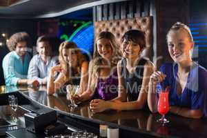 Smiling friends standing together at bar counter