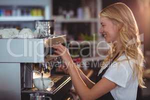 Smiling waitress making cup of coffee
