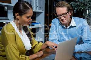 Business executives discussing over laptop