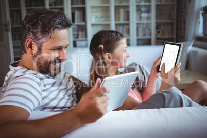 Father and daughter using digital tablet in living  room