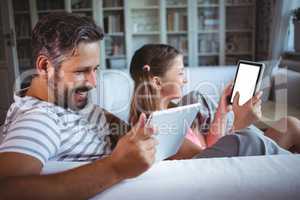 Father and daughter using digital tablet in living  room