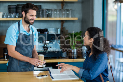 Waiter serving a cup of cold coffee to customer at table