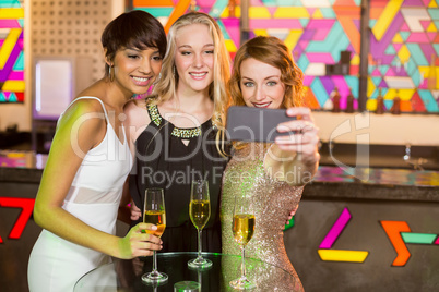 Female friends taking selfie from mobile phone while having champagne