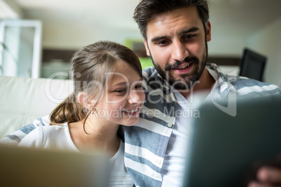 Father and daughter using laptop and digital tablet in the living room