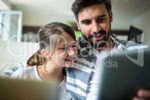 Father and daughter using laptop and digital tablet in the living room
