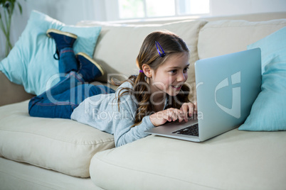 Girl relaxing on sofa and using laptop in the living room