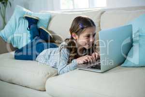 Girl relaxing on sofa and using laptop in the living room