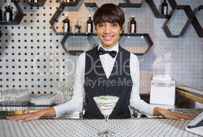 Waitress standing in bar counter with glass of cocktail