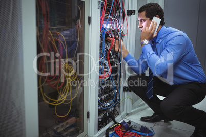 Technician talking on mobile phone while analyzing server