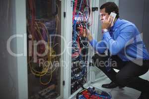 Technician talking on mobile phone while analyzing server