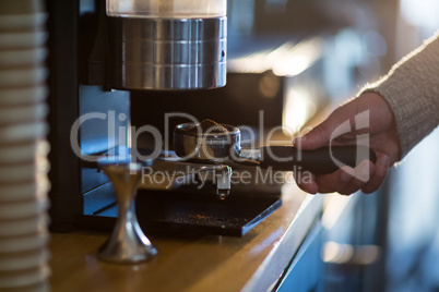 Waiter holding portafilter filled with ground coffee