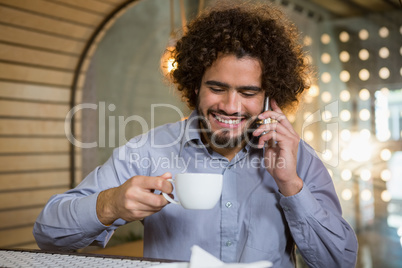 Man talking on mobile phone while having cup of tea