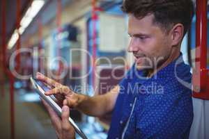 Handsome man using digital tablet in train