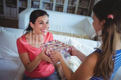 Happy mother receiving a surprise gift from her daughter