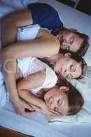 Family sleeping on bed