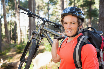Portrait of male mountain biker carrying bicycle in the forest