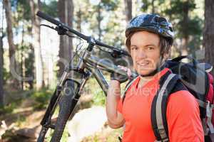 Portrait of male mountain biker carrying bicycle in the forest