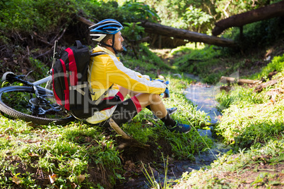 Mountain biker sitting near a stream and looking at nature