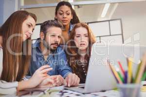 Male coworker with businesswomen using laptop at desk