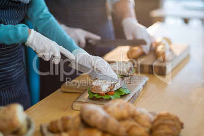 Waiter chopping bread roll and sandwich on chopping board in cafÃ?Â©