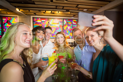 Group of friends taking selfie from mobile phone while having cocktail