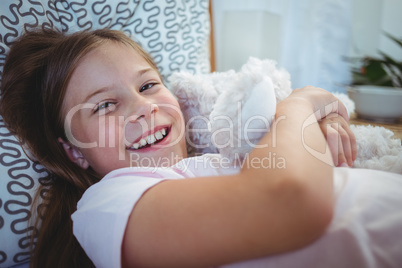Happy girl lying with a teddy bear
