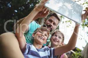 Father and kids taking a selfie with digital tablet