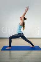 Woman performing warrior pose on exercise mat