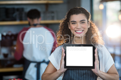 Smiling waitress showing digital tablet at counter in cafÃ?Â©