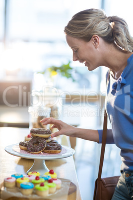 Excited woman selecting doughnuts from cake stand