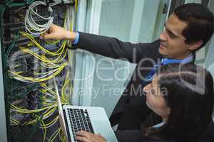 Technicians using laptop while analyzing server