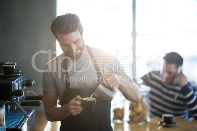Smiling waiter making cup of coffee at counter