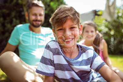 Smiling boy sitting in garden with father and sister