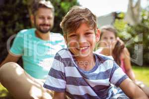 Smiling boy sitting in garden with father and sister