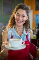 Portrait of smiling female staff serving a cup of coffee