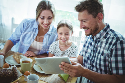 Family using digital tablet while having breakfast