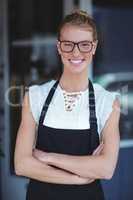 Portrait of smiling waitress standing with arms crossed