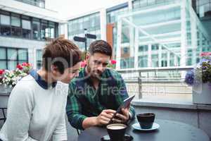 Businesspeople discussion on digital tablet while having coffee