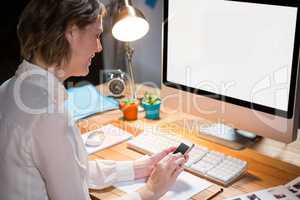 Businesswoman using mobile phone at her desk