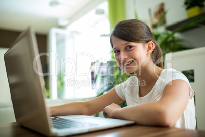 Portrait of smiling girl with laptop in the living room