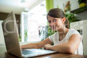 Portrait of smiling girl with laptop in the living room