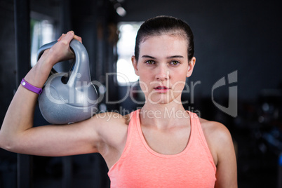 Portrait of serious female athlete holding kettlebell in gym