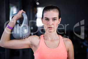 Portrait of serious female athlete holding kettlebell in gym